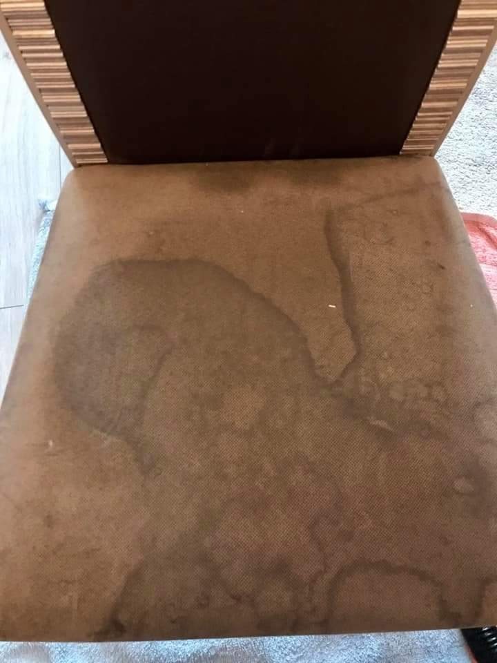 Brązowe krzesło tapicerowane z wyraźnymi plamami po czyszczeniu, widoczne mokre ślady na siedzisku.