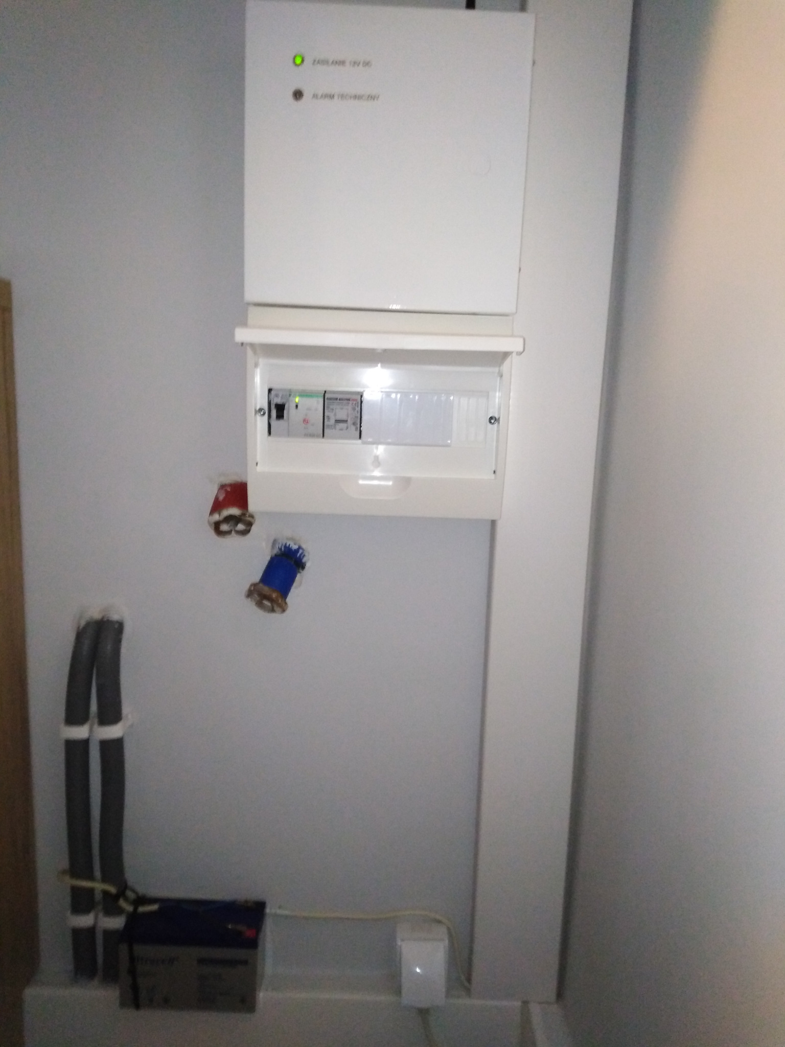 Zamontowana centrala sterująca systemem detekcji alarmów technicznych z detekcją zalania i ulatniania gazu, z powiadamianiem GSM. Widoczne przewody i akumulator.