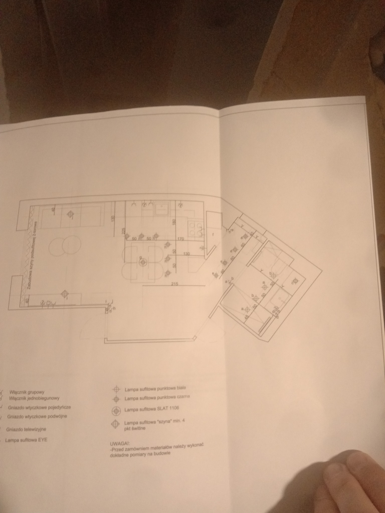 Plan elektryki mieszkania na kartce papieru, widoczne rozmieszczenie lamp sufitowych i gniazdek, z uwzględnieniem wymiarów.