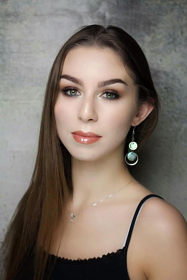 Portret młodej kobiety z profesjonalnym, wieczorowym makijażem, obejmującym błyszczące cienie na powiekach i błyszczyk na ustach, uzupełniony o srebrną biżuterię i kolczyki z elementami masy...