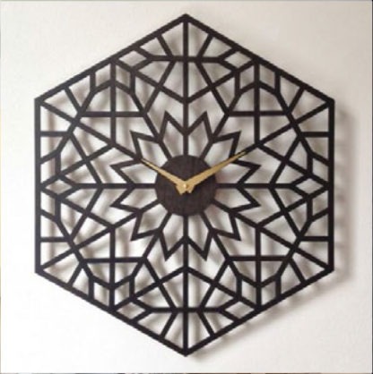 Dekoracyjny zegar ścienny o heksagonalnym kształcie z ażurowym wzorem geometrycznym, wykonany z ciemnego metalu. Wskazówki zegara są złote.