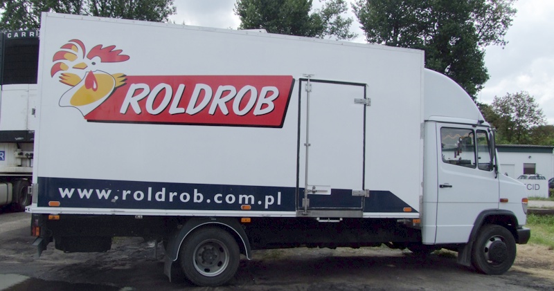 Biała ciężarówka chłodnia z logo firmy Roldrob i adresem strony internetowej, zaparkowana na zewnątrz.