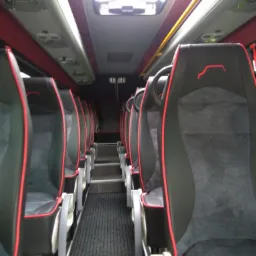 Wnętrze autobusu z czarno-szarymi fotelami z czerwonymi akcentami, widok z przodu w kierunku schodów, Lisia Góra.