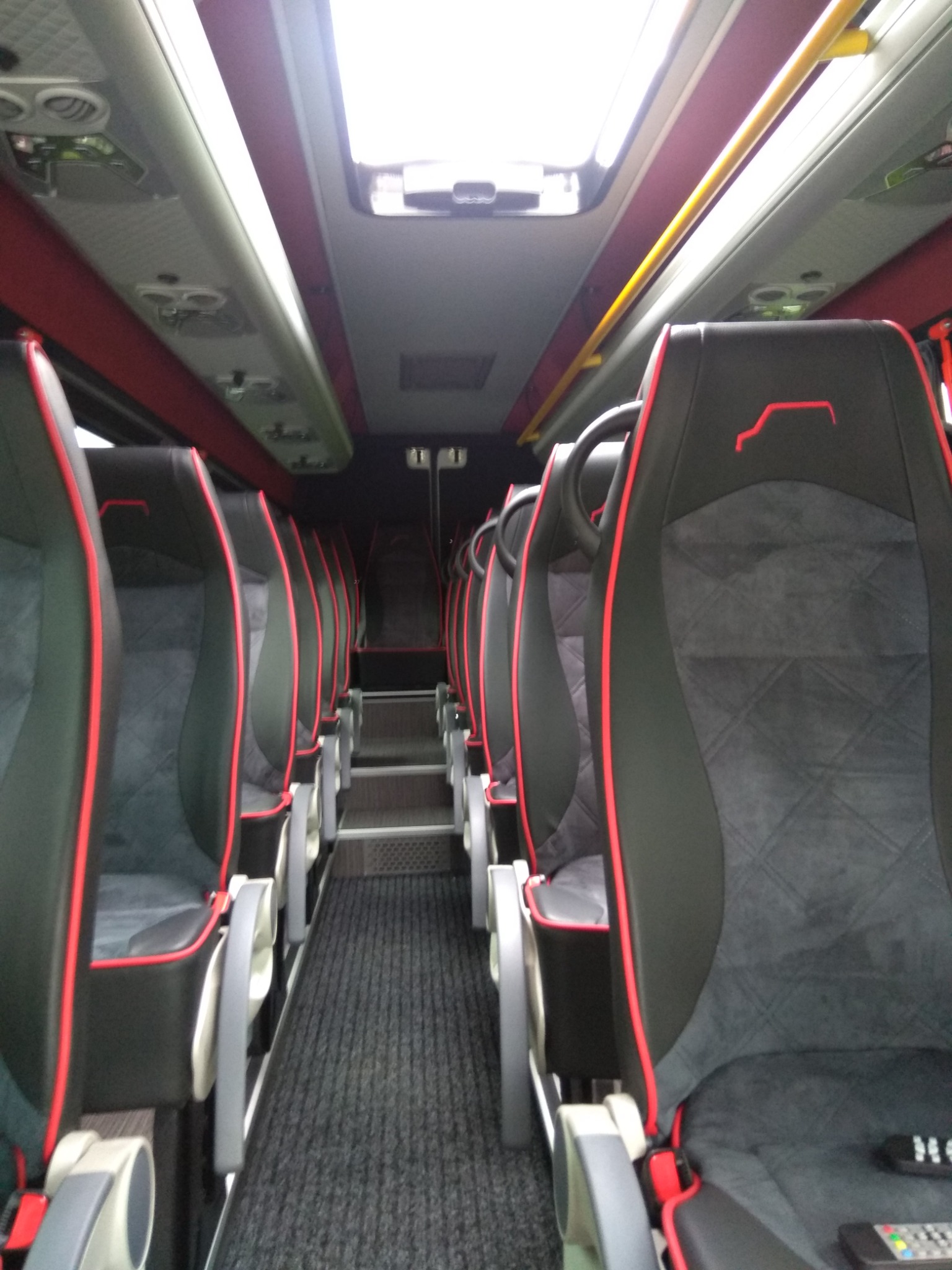 Wnętrze autobusu z czarno-szarymi fotelami z czerwonymi akcentami, widok z przodu w kierunku schodów, Lisia Góra.