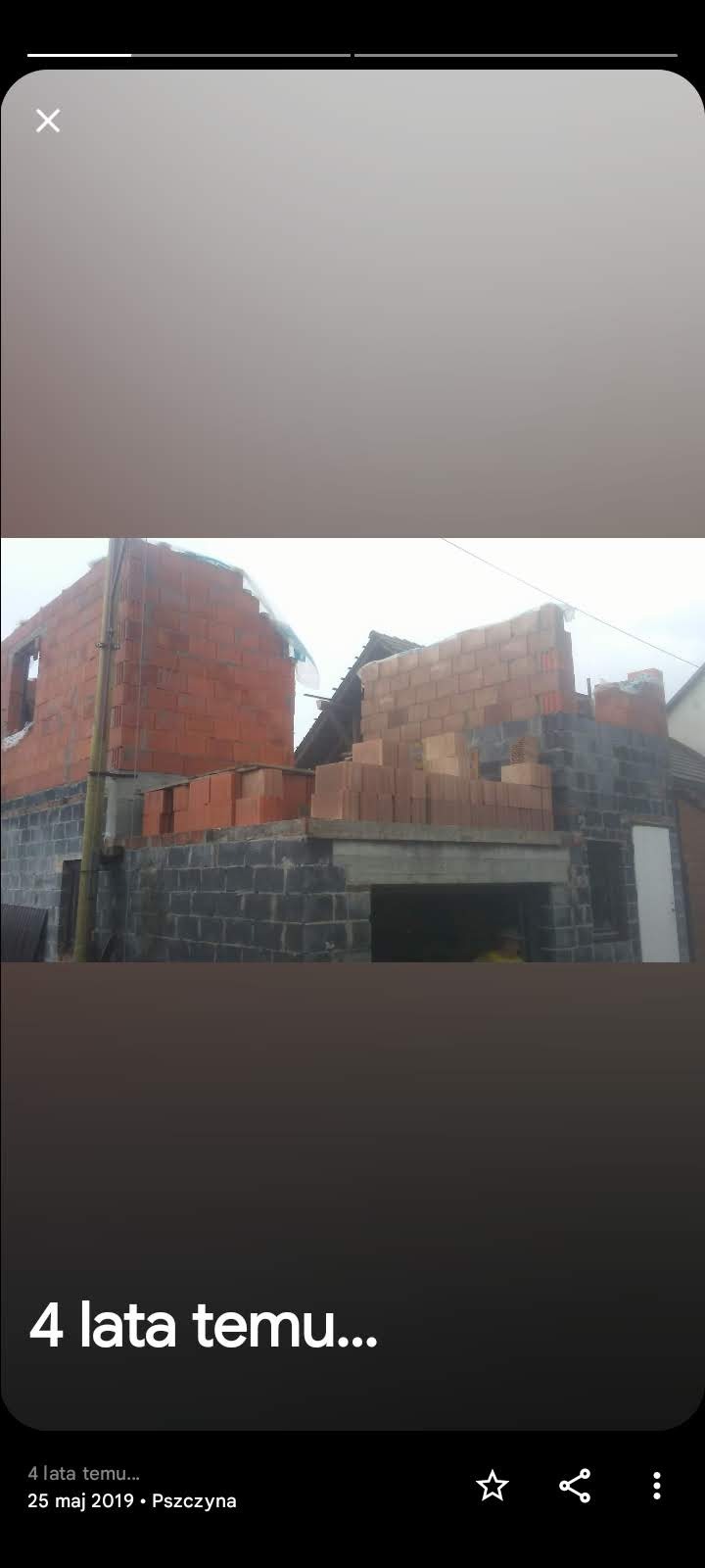 Budowa domu jednorodzinnego w trakcie wznoszenia murów z bloczków betonowych i cegły ceramicznej, widoczny zarys okna i dachu sąsiedniego budynku.