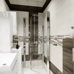 Nowoczesna łazienka z kabiną prysznicową typu walk-in, umywalką nablatową, podwieszaną toaletą i dekoracyjnymi płytkami w odcieniach bieli, szarości i brązu, uzupełniona o minimalistyczne akcesoria.