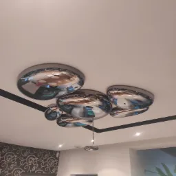 Nowoczesny sufit z chromowanymi, okrągłymi lampami, tworzącymi efektowną kompozycję; widoczne odbicia wnętrza w lampach.