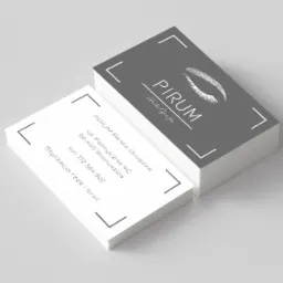 Stos wizytówek z logo firmy 'PIRUM Beata Gruszka', specjalizującej się w stylizacji rzęs i brwi, na jasnoszarym tle.