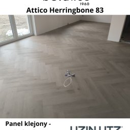 Miasto Podłóg Sp. z o.o. - Jasnoszara podłoga z paneli ułożonych we wzór jodełki francuskiej w nowym pomieszczeniu z dużym oknem. Na podłodze leży zabawka.