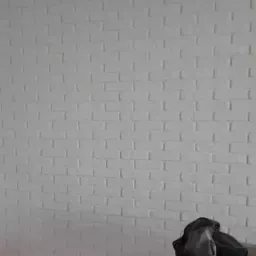 Ściana z białej cegły, z widocznymi niedoskonałościami w fugach i nierównym wykończeniem, sugerująca etap prac wykończeniowych, z szmatką i narzędziem na podłodze.