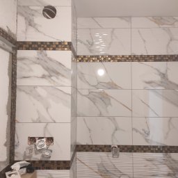 Mom-Bud Usługi Remontowo-Budowlane Łukasz Mortel - Ściana łazienki w trakcie remontu z białymi płytkami imitującymi marmur, ozdobnymi pasami mozaiki, puszkami elektrycznymi bez osprzętu i narzędziami na podłodze.