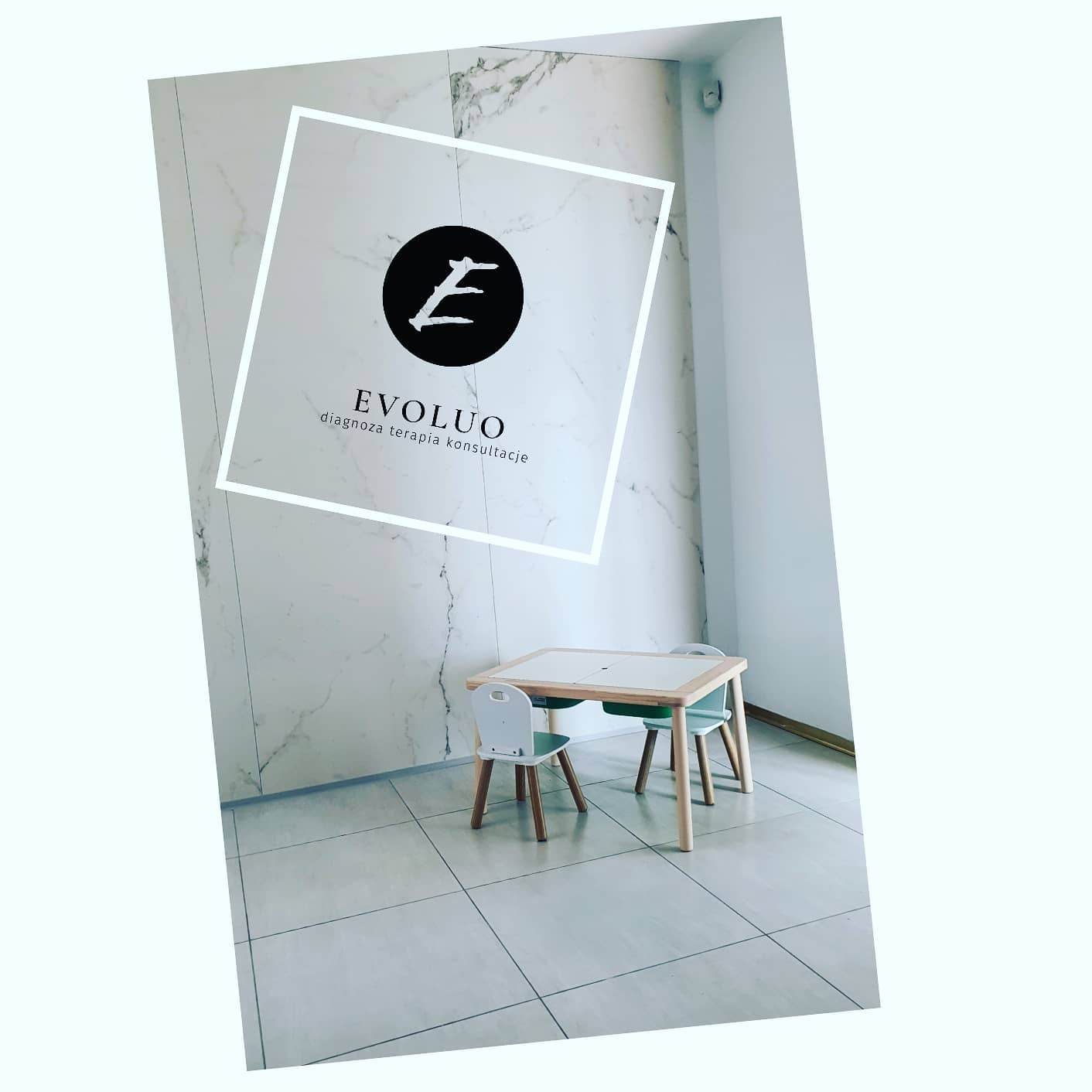 Jasne wnętrze gabinetu z dziecięcym stolikiem i krzesłami, na ścianie logo firmy Evoluo oferującej diagnozę, terapię i konsultacje.