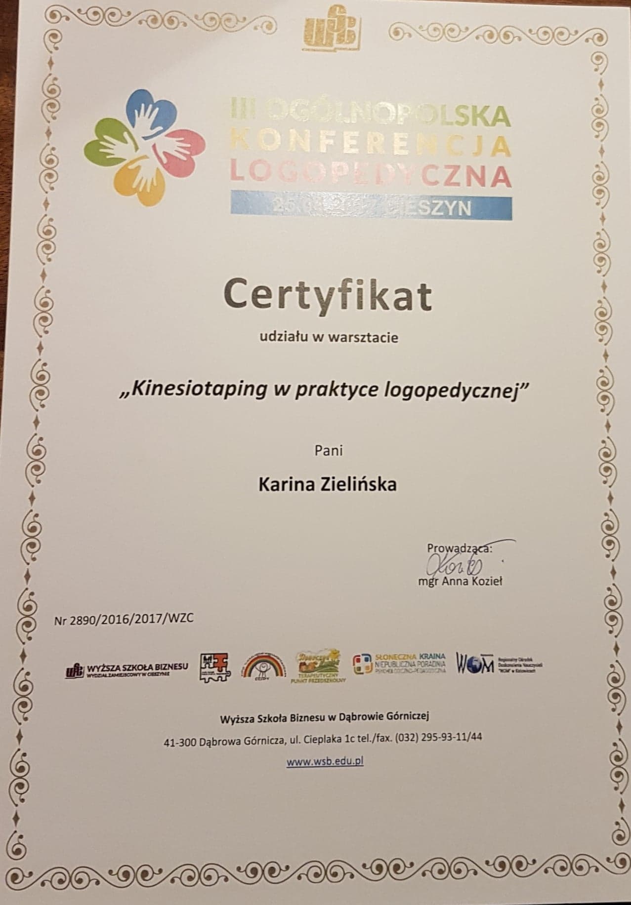 Certyfikat ukończenia warsztatu 'Kinesiotaping w praktyce logopedycznej' dla Kariny Zielińskiej, wydany przez Wyższą Szkołę Biznesu w Dąbrowie Górniczej, z logo uczelni i innych organizacji.
