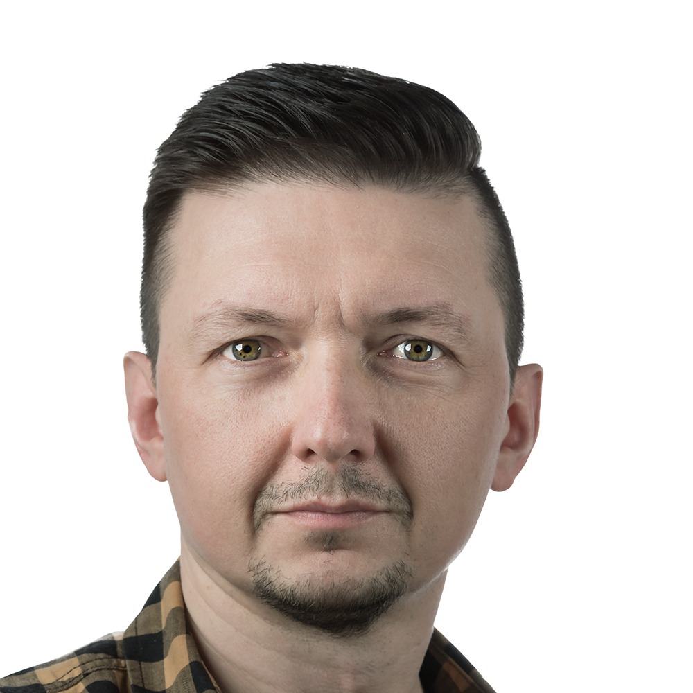 Portret mężczyzny w koszuli w kratę, z krótką brodą i starannie ułożonymi włosami, na białym tle.