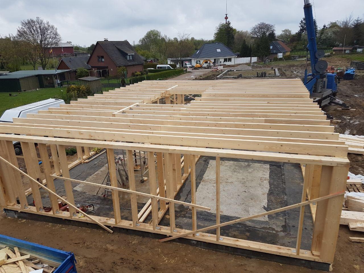 Konstrukcja szkieletowa domu jednorodzinnego w Gorzowie Wielkopolskim, widok z góry na fundamenty i drewniane belki stropowe, w tle zabudowa jednorodzinna i dźwig.