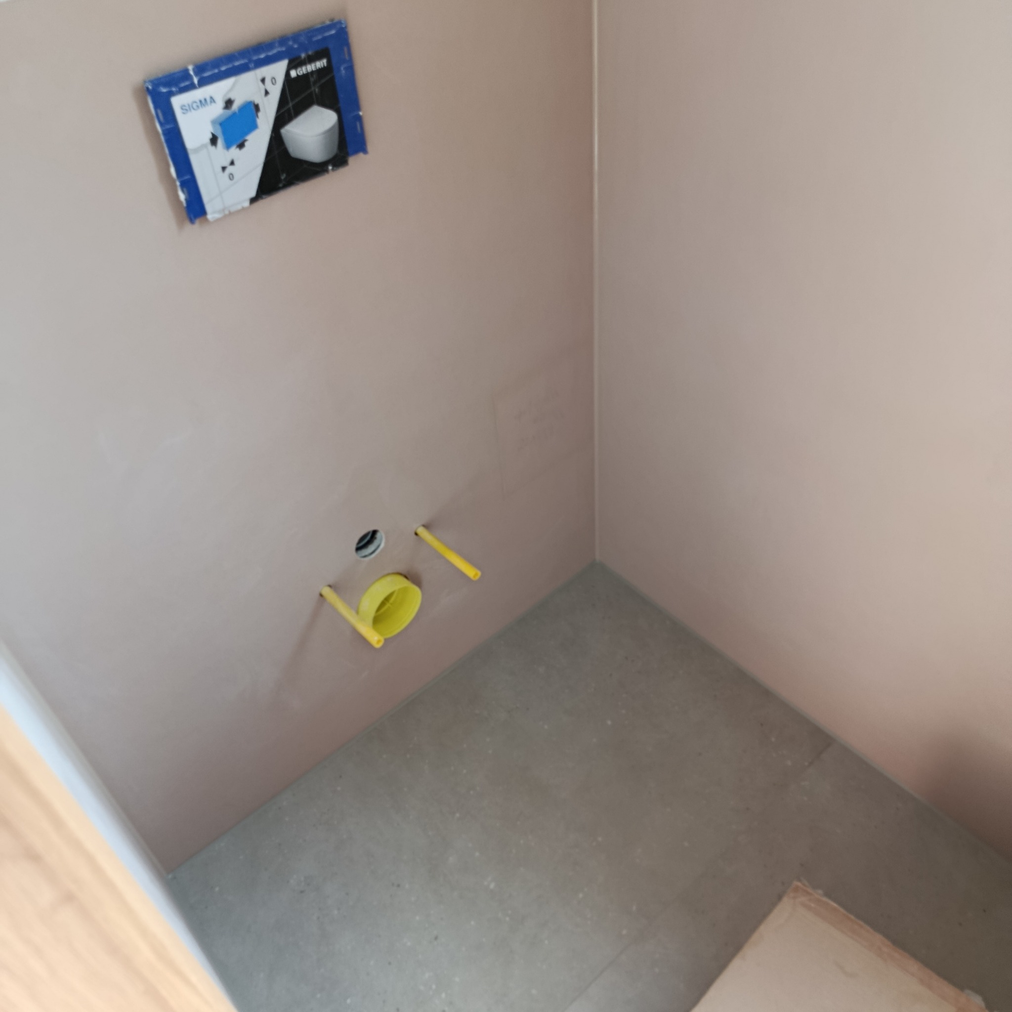 Przygotowana ściana w łazience z instalacją podtynkową WC, widoczne rury i stelaż. Ściana po szpachlowaniu, gotowa do dalszych prac wykończeniowych.