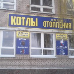 Studio 11 - Budynek z cegły z szyldem reklamującym kotły i ogrzewanie, oraz banery w oknach z informacjami o kotłach, piecach i materiałach instalacyjnych.