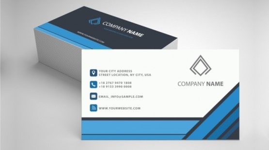 Stos wizytówek z nowoczesnym, geometrycznym wzorem w odcieniach szarości i błękitu, obok leży pojedyncza wizytówka z danymi teleadresowymi i logo firmy.