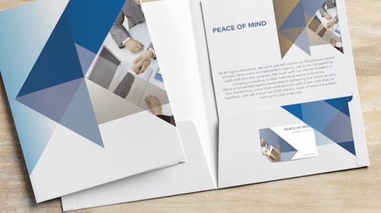 Otwarta biała teczka z geometrycznym wzorem w odcieniach niebieskiego, zawierająca wkładkę z tekstem 'Peace of Mind', w tle zdjęcie uścisku dłoni podczas spotkania biznesowego, a w wycięciu...