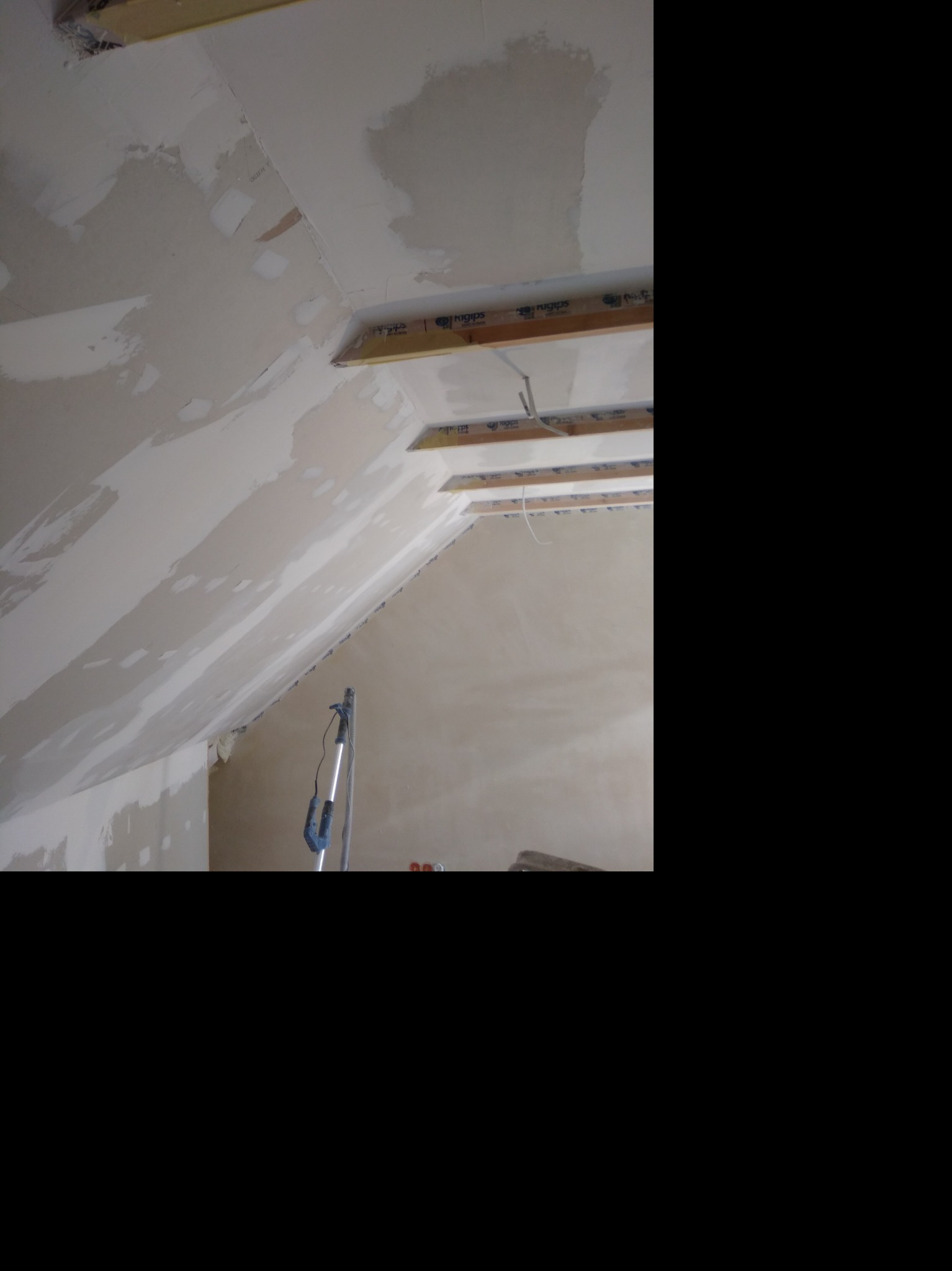 Montaż płyty karton gips na skośnym poddaszu, widoczne drewniane belki konstrukcyjne i szpachlowane łączenia płyt.