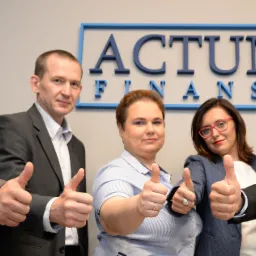 Zespół finansowy Actum prezentuje gest aprobaty z uniesionymi kciukami na tle logo firmy w błękitnej ramie.