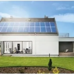 Nowoczesny dom jednorodzinny z panelami słonecznymi na dachu, widok z ogrodu w słoneczny dzień.