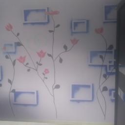 Pb-Bud - Ściana pomalowana w białe tło z motywem kwiatów i geometrycznych kształtów w odcieniach różu i błękitu, widoczne ślady po wałku.