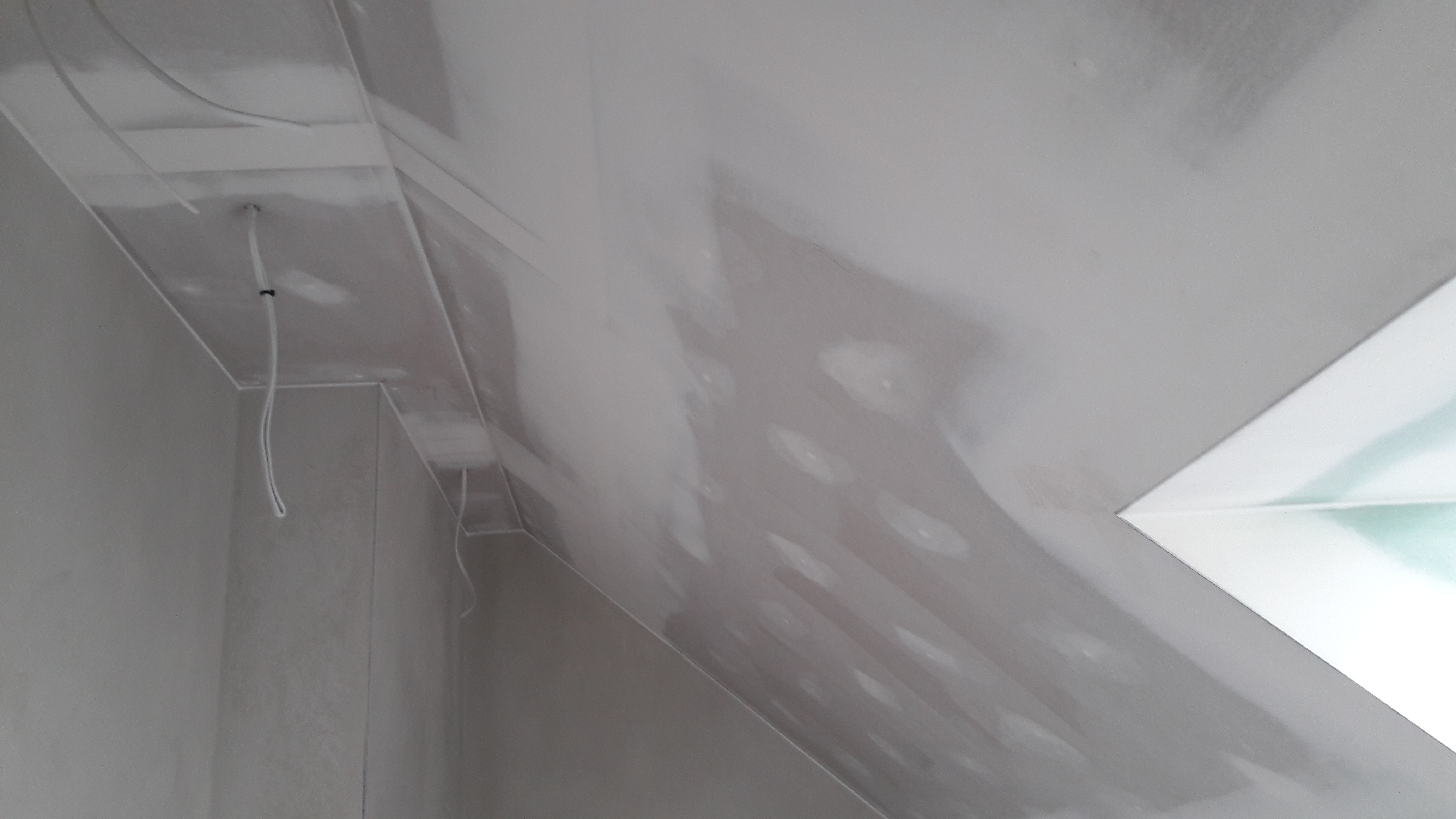 Sufit poddasza po szpachlowaniu, widoczne łączenia płyt i przewody elektryczne w rogu pomieszczenia.