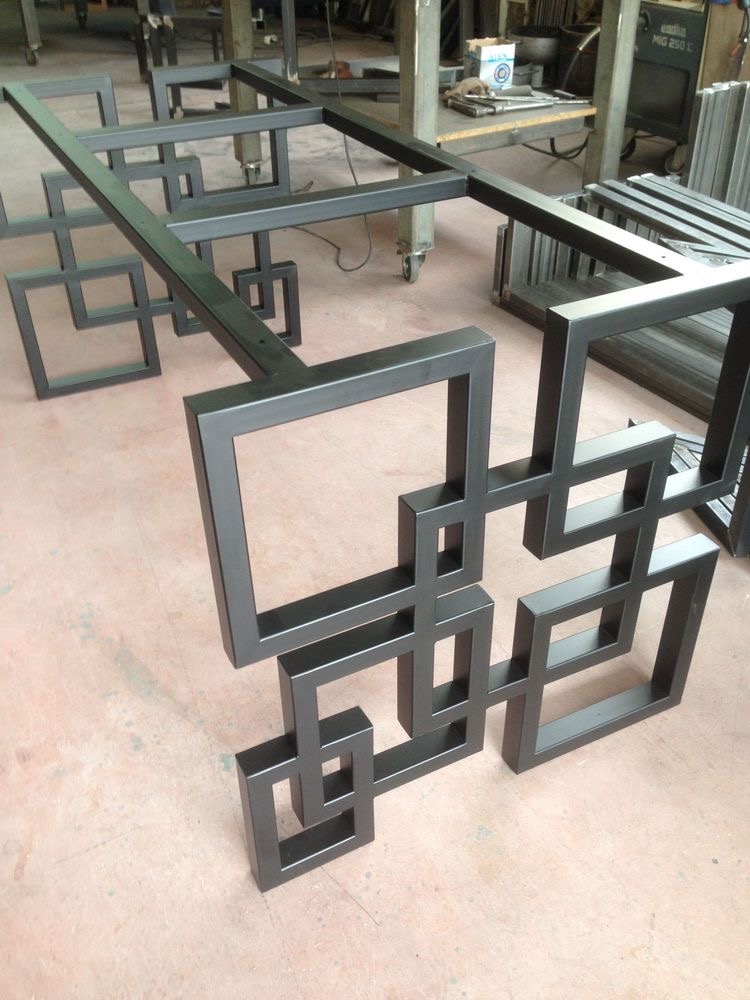 Metalowa konstrukcja z profili kwadratowych, spawana w geometryczny wzór, widoczne ślady obróbki na podłodze warsztatu.