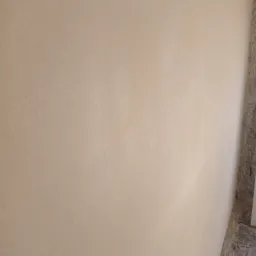 Świeżo nałożony, jasny tynk na ścianie wewnętrznej, widoczny fragment podłogi z resztkami zaprawy.