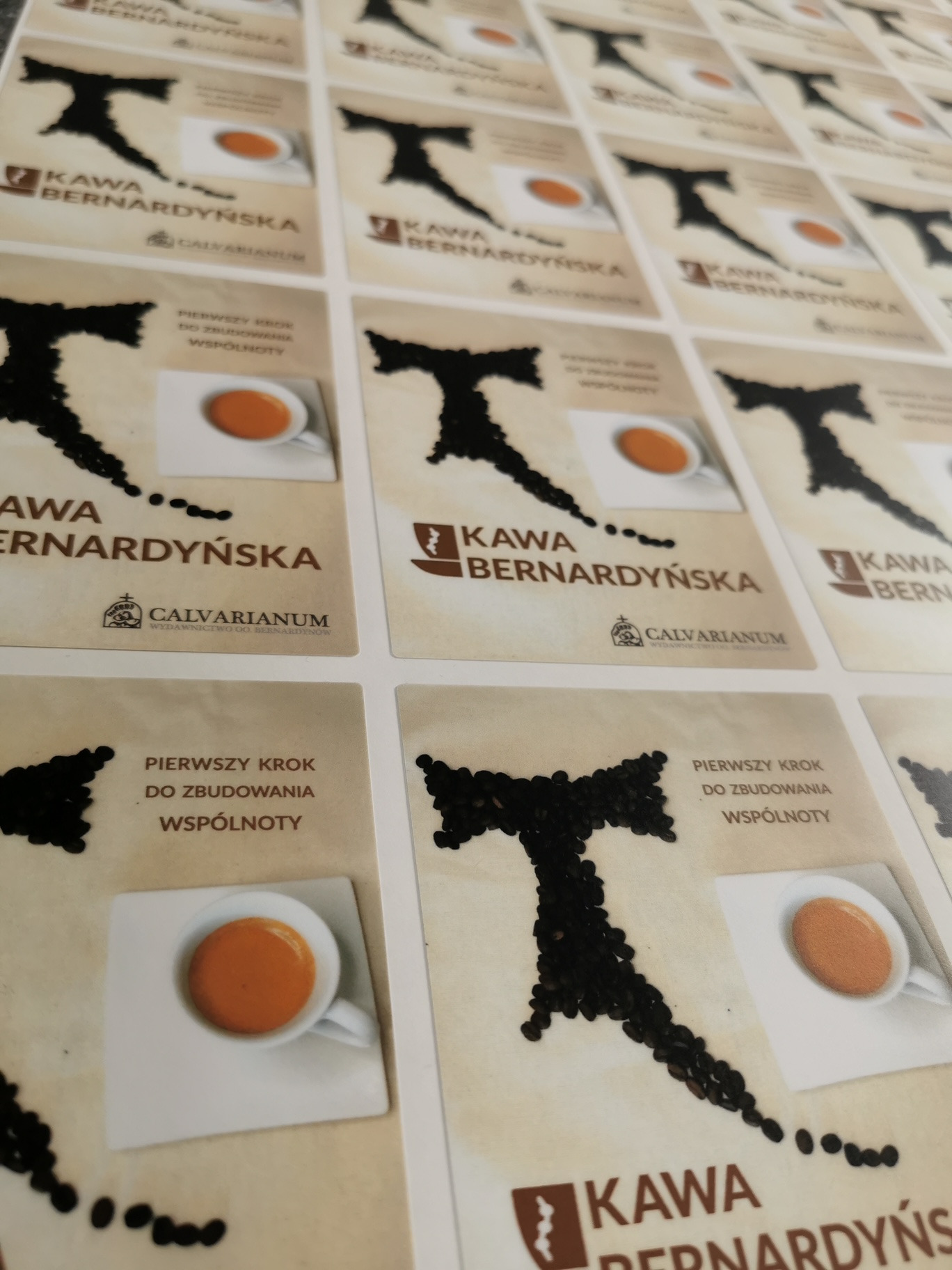 Arkusze z identycznymi etykietami kawy Bernardyńskiej, prezentujące logo z ziaren kawy i filiżankę espresso na kremowym tle.