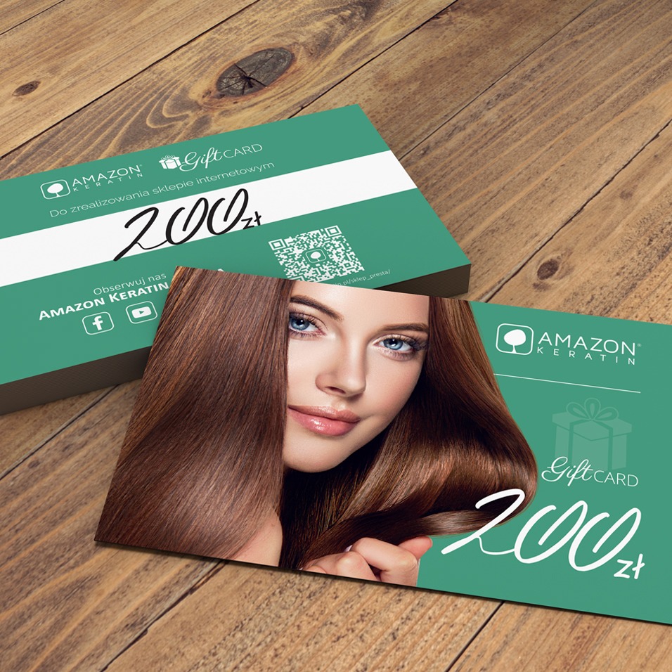 Dwa zielone vouchery prezentowe Amazon Keratin o nominale 200 zł, leżące na drewnianym stole, z wizerunkiem kobiety o brązowych włosach i niebieskich oczach.