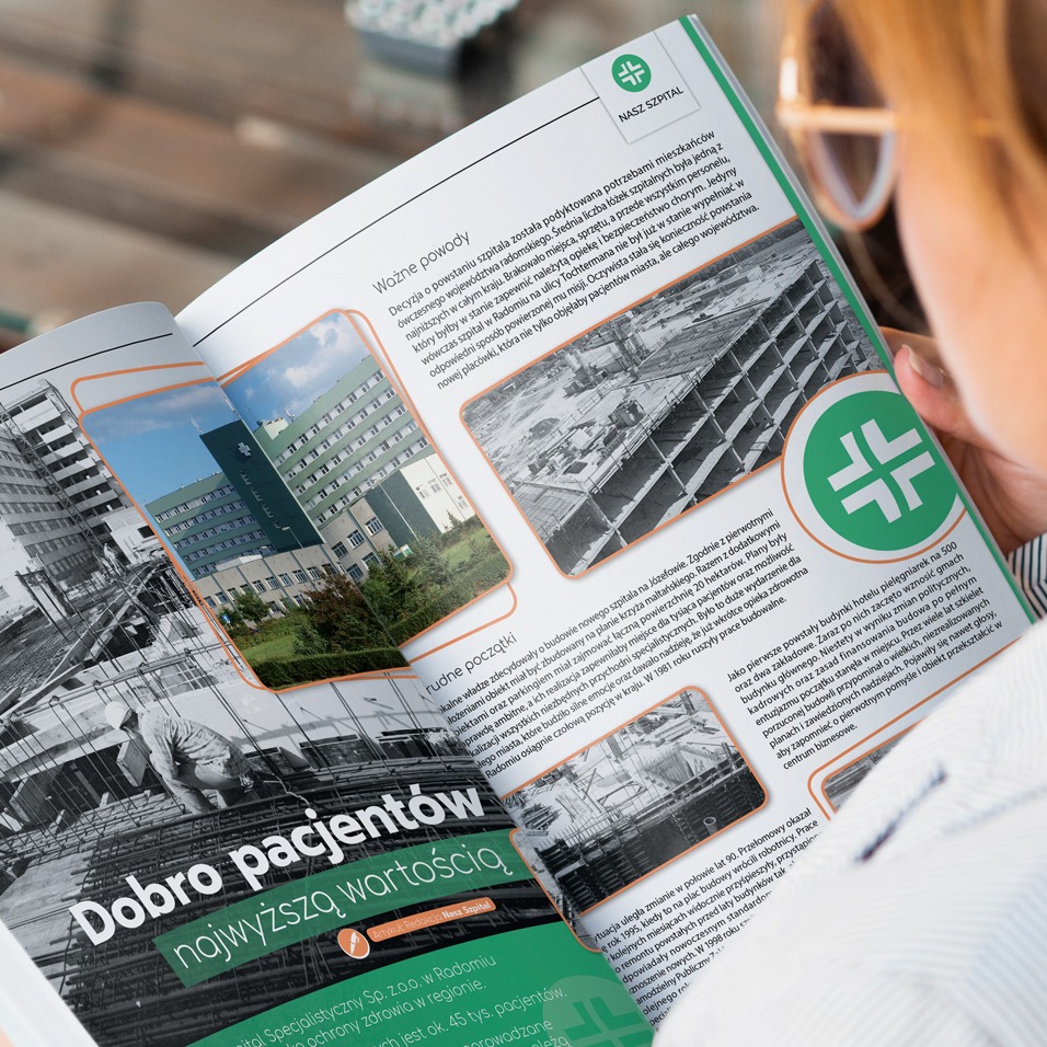 Otwarta gazeta z artykułem o historii szpitala, zdjęcia budynku szpitala z zewnątrz i w trakcie budowy, widoczne ręce osoby trzymającej gazetę.