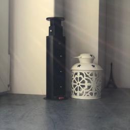 Dece - Meble - Czarne, metalowe podparcie blatu z regulacją wysokości stoi obok białego lampionu z wyciętymi wzorami na szarym blacie, z miniaturą wieży Eiffla w tle i promieniami słonecznymi.