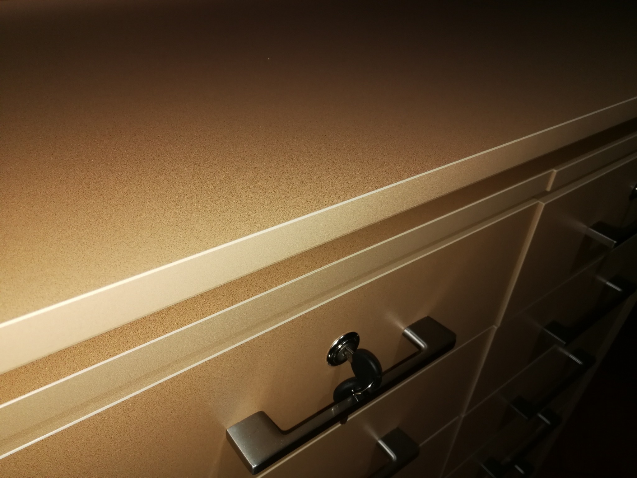 Beżowa szafa z szufladami zamykanymi na klucz, wykonana na wymiar w Dębicy, z widocznymi metalowymi uchwytami.