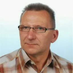 Portret mężczyzny w okularach, ubrany w koszulę w kratę, na jasnym tle.