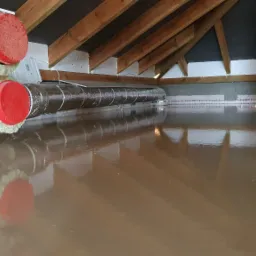 Świeżo wylana, mokra wylewka anhydrytowa w poddaszu z widocznymi rurami wentylacyjnymi zaizolowanymi wełną mineralną i folią aluminiową z czerwonymi zaślepkami.