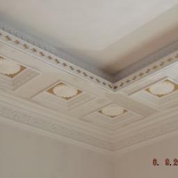 Q - Rem - Dekoracyjny sufit z białymi, kwadratowymi kasetonami z motywem kwiatowym i złoconym obramowaniem, wykończony sztukaterią.