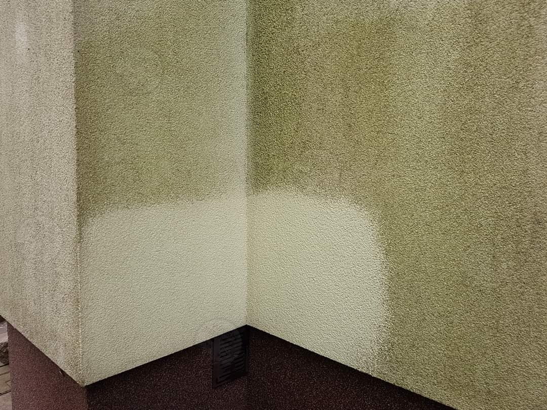 Fragment elewacji budynku z widocznym efektem mycia ciśnieniowego, gdzie górna część ściany jest zabrudzona, a dolna czysta, ukazując kontrast przed i po czyszczeniu.