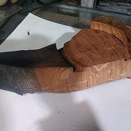 Marcin Birski - Dwa bloki obrobionego drewna, jeden opalony na czarno, drugi w naturalnym odcieniu, leżące na białym papierze w warsztacie.