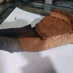 Dwa bloki obrobionego drewna, jeden opalony na czarno, drugi w naturalnym odcieniu, leżące na białym papierze w warsztacie.