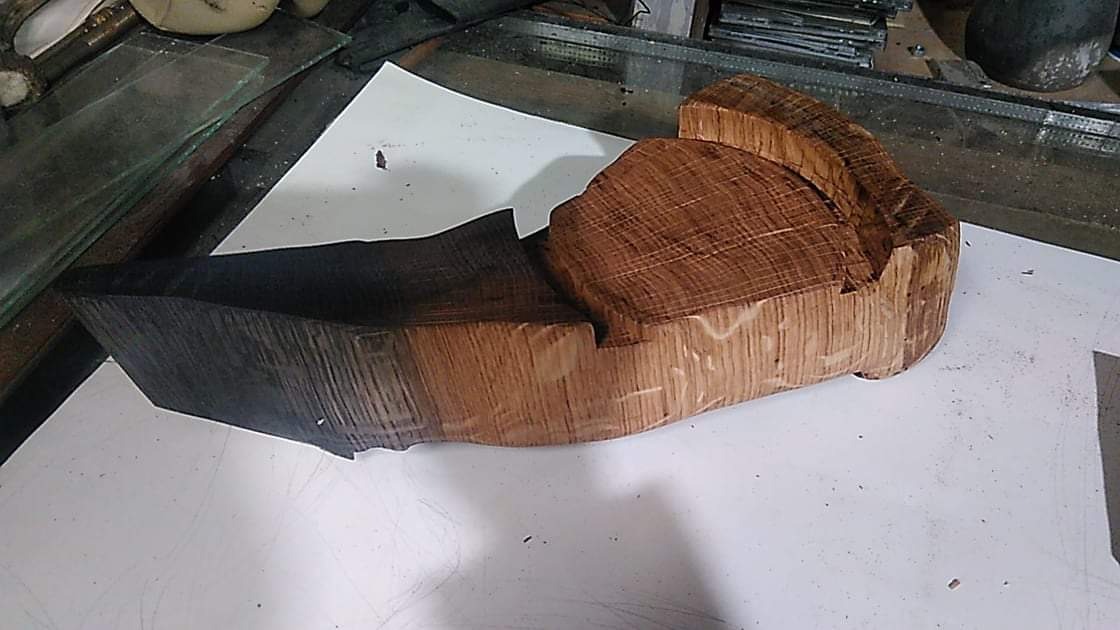 Dwa bloki obrobionego drewna, jeden opalony na czarno, drugi w naturalnym odcieniu, leżące na białym papierze w warsztacie.