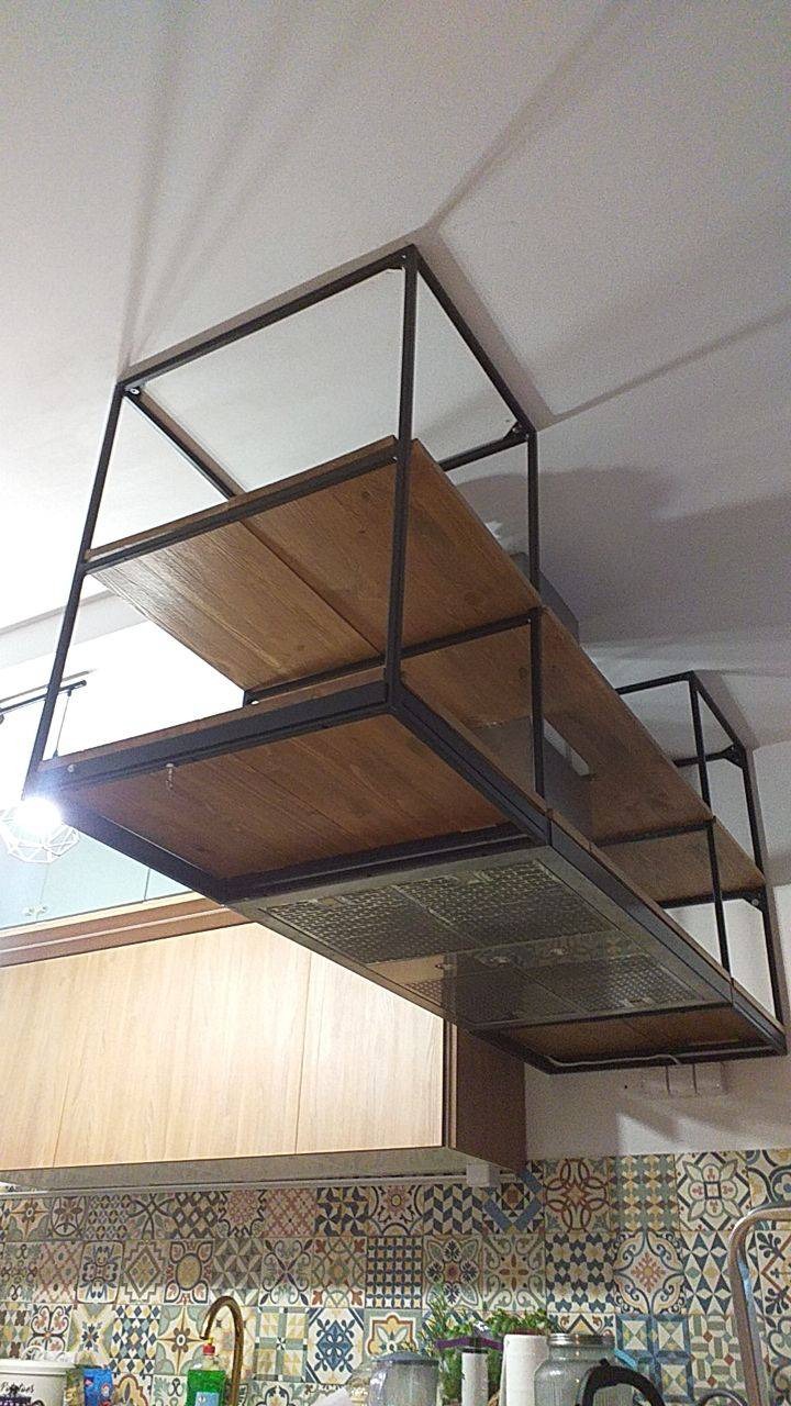 Metalowa konstrukcja z drewnianymi półkami zawieszona pod sufitem w kuchni, nad okapem i płytkami ceramicznymi w stylu patchwork