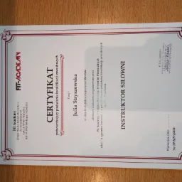 Certyfikat ukończenia szkolenia dla instruktora siłowni, wydany przez Fit Academy dla Julii Stryszewskiej, z ozdobną bordiurą i logo firmy.