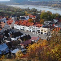 Wzgórze Zamkowe Sp. z o.o. - Kazimierz Dolny z lotu ptaka w jesiennej scenerii, widok na Rynek z charakterystycznymi kamienicami i Wisłę w tle.