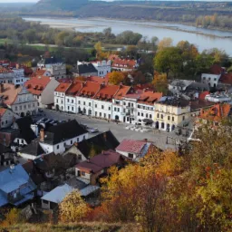 Kazimierz Dolny z lotu ptaka w jesiennej scenerii, widok na Rynek z charakterystycznymi kamienicami i Wisłę w tle.