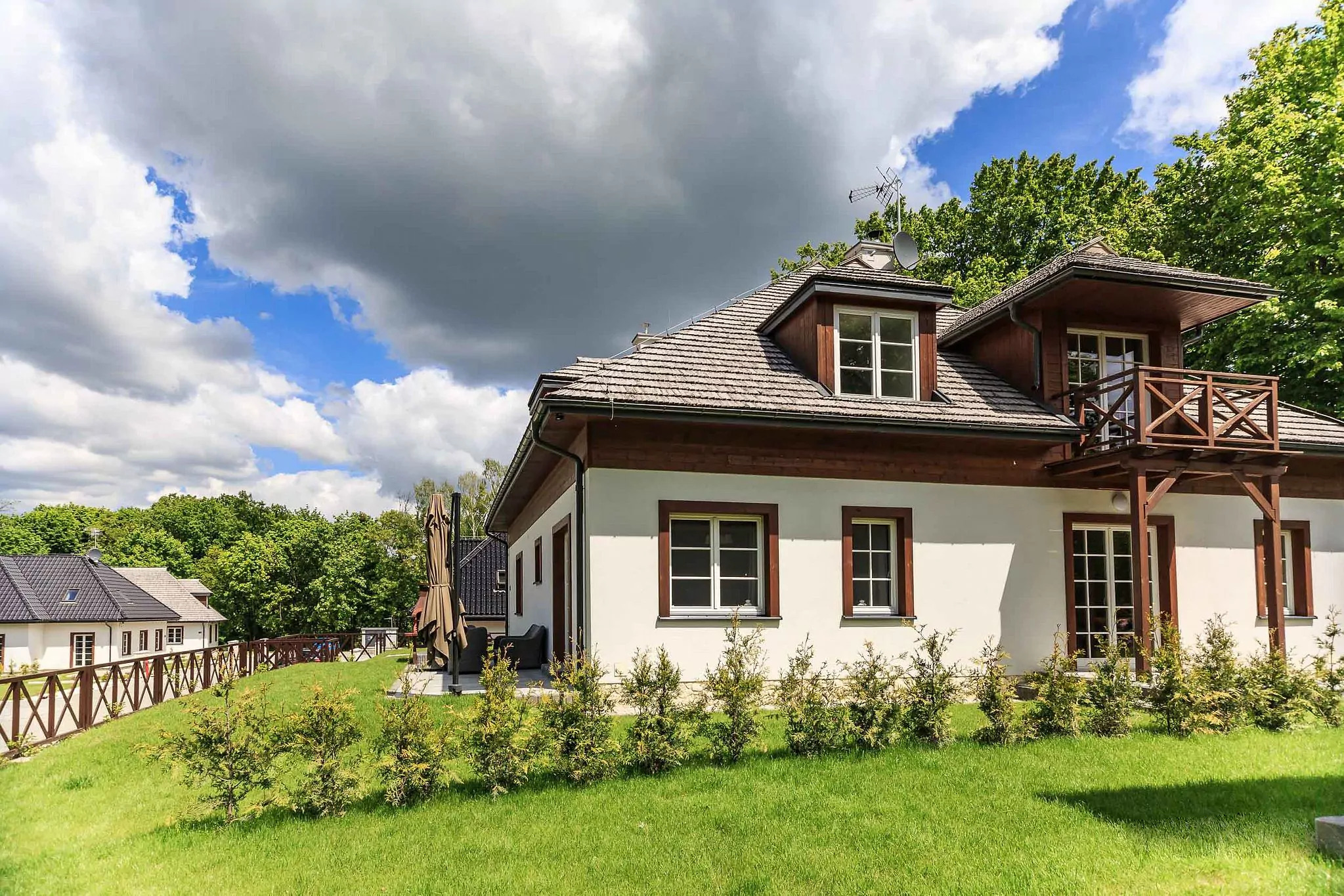 Elewacja budynku z drewnianymi elementami w Kazimierzu Dolnym, widok z zewnątrz na tle zieleni i pochmurnego nieba.