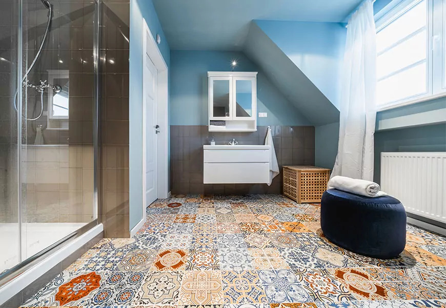 Jasna łazienka na poddaszu z kabiną prysznicową, białą szafką z umywalką, dekoracyjną podłogą z płytek oraz niebieskimi ścianami.