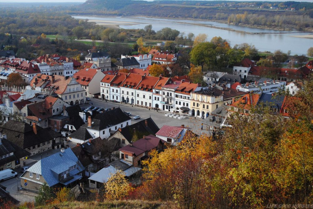 Kazimierz Dolny z lotu ptaka w jesiennej scenerii, widok na Rynek z charakterystycznymi kamienicami i Wisłę w tle.