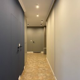 Foremen Sp. z o.o. - Wnętrze korytarza w odcieniach szarości i beżu, z ciemnogranatową szafą w zabudowie, punktowym oświetleniem sufitowym i podłogą imitującą kamień.